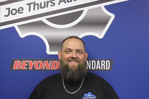 Smiling man in front of sign with logo