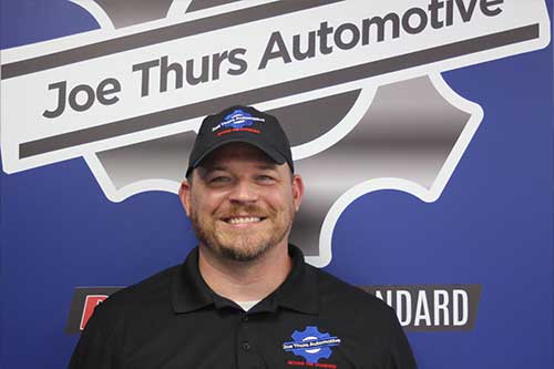 Man in front of Joe Thurs Automotive sign