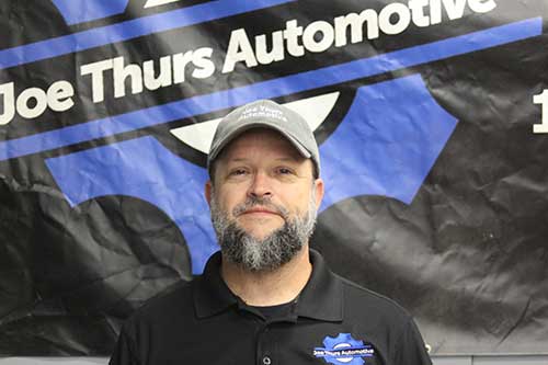 Man in front of Joe Thurs Automotive sign