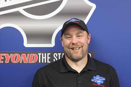 Man smiling at automotive repair shop wall