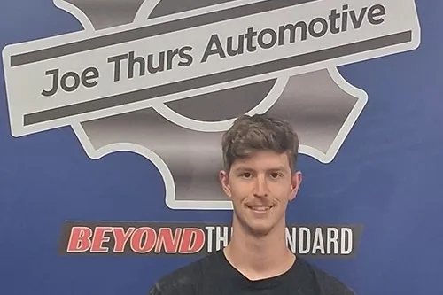 Man standing before Joe Thurs Automotive sign